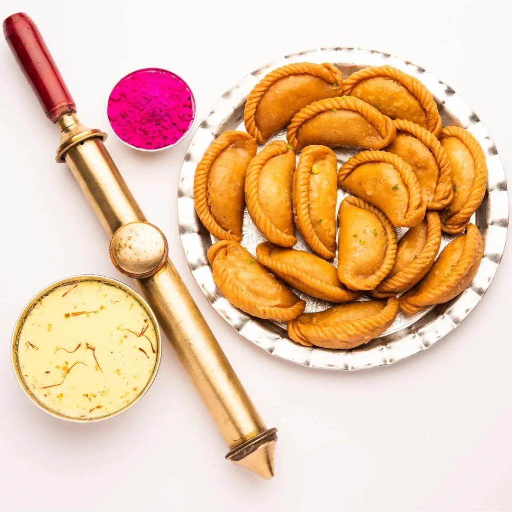 Traditional Holi sweets like gujiya and thandai arranged on a decorative plate.